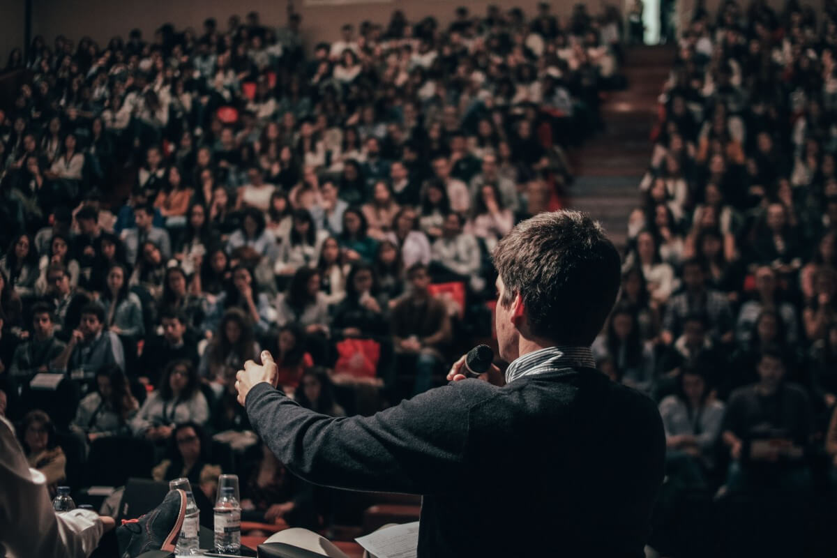 Guest Speakers Lecturing At Unviersity With Crowd In The Backgroud